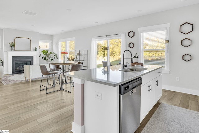 kitchen with a center island with sink, white cabinetry, light hardwood / wood-style flooring, dishwasher, and sink