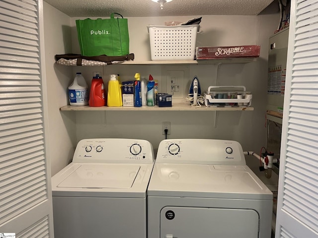 clothes washing area with a textured ceiling, electric panel, and separate washer and dryer