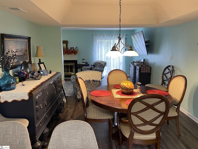 dining space featuring an inviting chandelier, dark hardwood / wood-style floors, and a raised ceiling