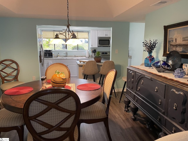 dining space with sink, a notable chandelier, and hardwood / wood-style flooring