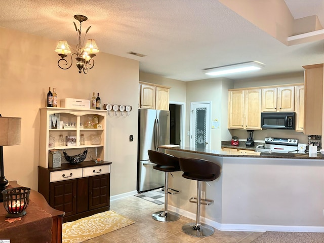 kitchen featuring a textured ceiling, a chandelier, stainless steel appliances, and hanging light fixtures