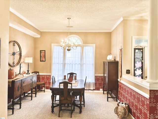 carpeted dining space featuring crown molding, a notable chandelier, a textured ceiling, and ornate columns