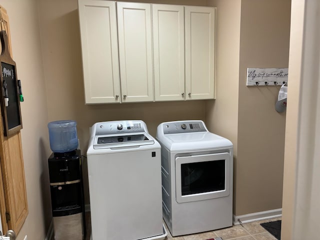 clothes washing area featuring light tile patterned floors, separate washer and dryer, and cabinets