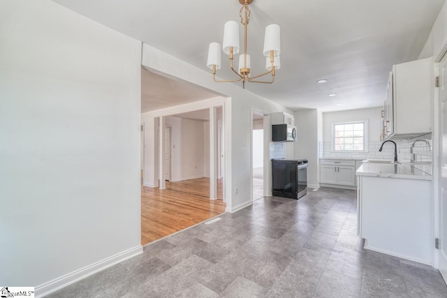 kitchen featuring stainless steel appliances, backsplash, sink, decorative light fixtures, and white cabinets