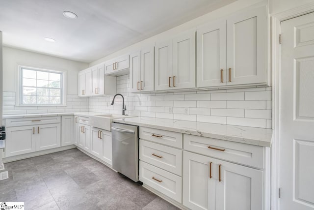 kitchen featuring backsplash, sink, light stone countertops, stainless steel dishwasher, and white cabinets