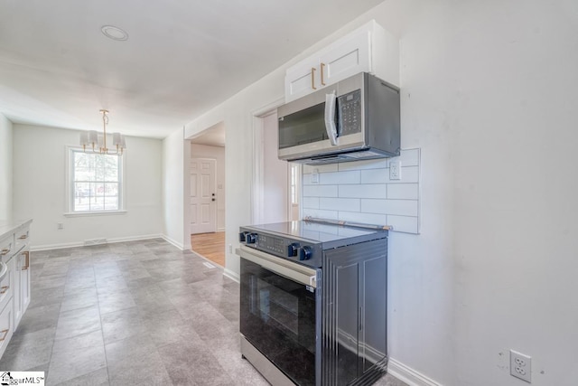 kitchen with an inviting chandelier, decorative backsplash, range with electric stovetop, and white cabinets