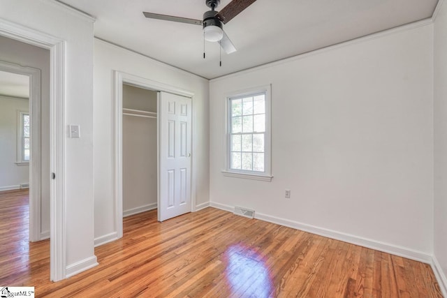 unfurnished bedroom with light hardwood / wood-style flooring, a closet, crown molding, and ceiling fan