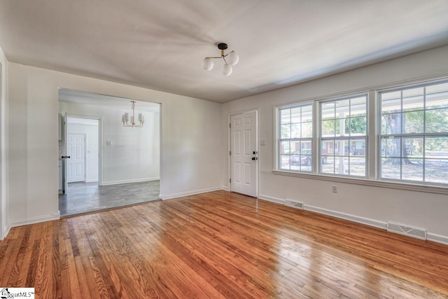 unfurnished room with hardwood / wood-style flooring and a chandelier