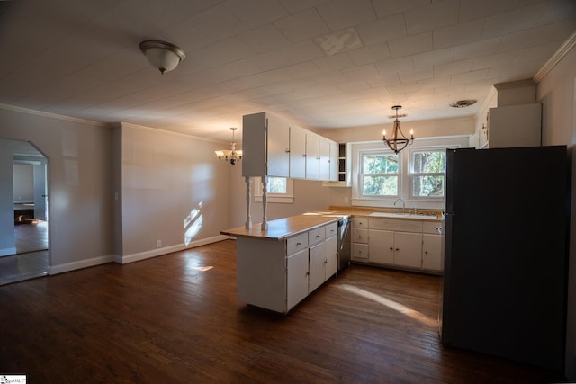 kitchen with black fridge, dark wood-type flooring, kitchen peninsula, decorative light fixtures, and white cabinets