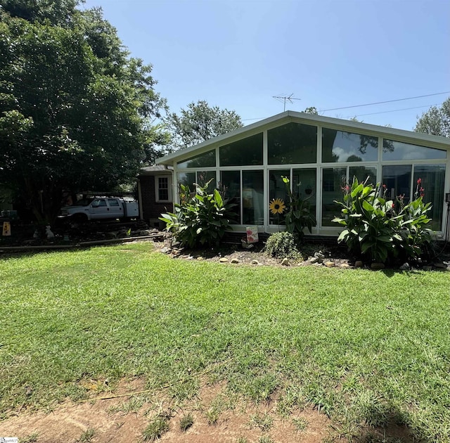 rear view of house featuring a sunroom and a yard