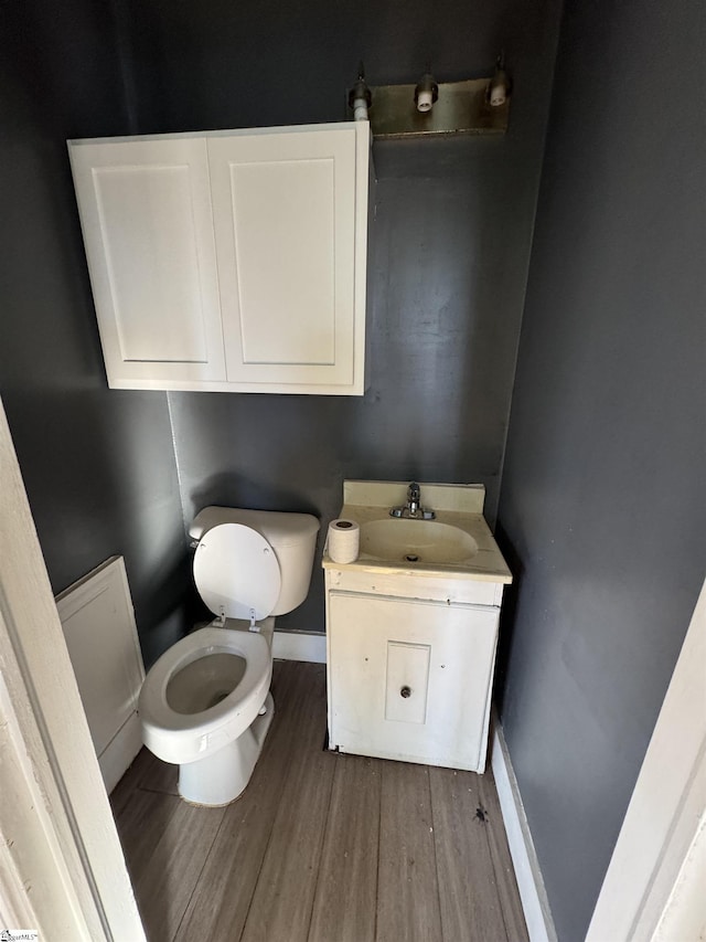 bathroom with hardwood / wood-style floors, vanity, and toilet