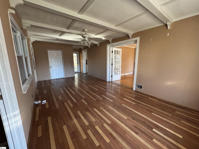 unfurnished living room with wood walls, coffered ceiling, ceiling fan, beam ceiling, and wood-type flooring