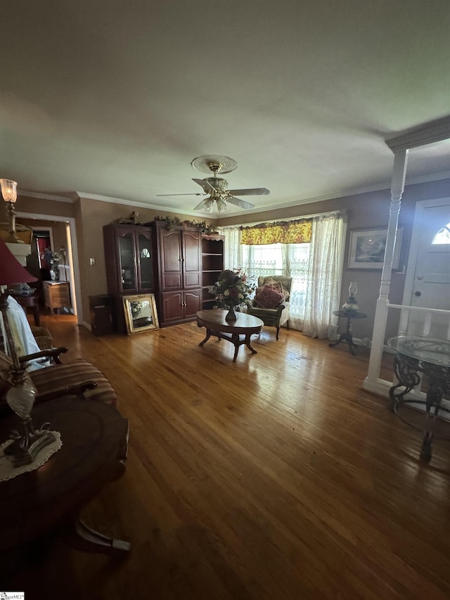 living room featuring dark hardwood / wood-style flooring, decorative columns, ceiling fan, and crown molding