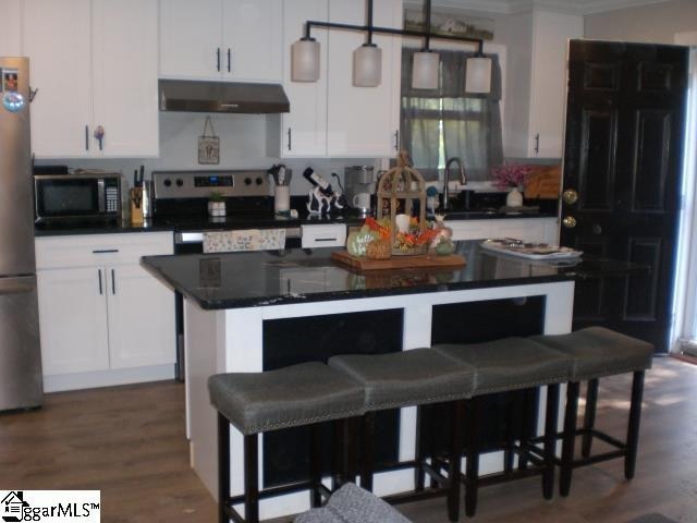 kitchen with white cabinets, a kitchen island, dark wood-type flooring, electric stove, and decorative light fixtures