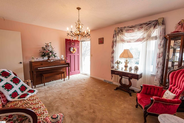 living area with a textured ceiling, a notable chandelier, carpet floors, and a healthy amount of sunlight