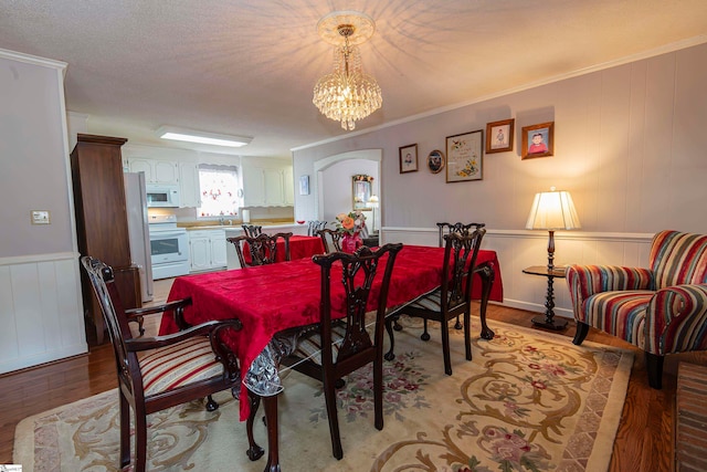 dining room with ornamental molding, a notable chandelier, and light wood-type flooring