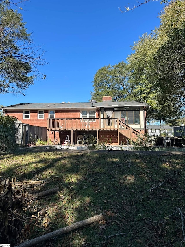 rear view of house featuring a lawn and a wooden deck