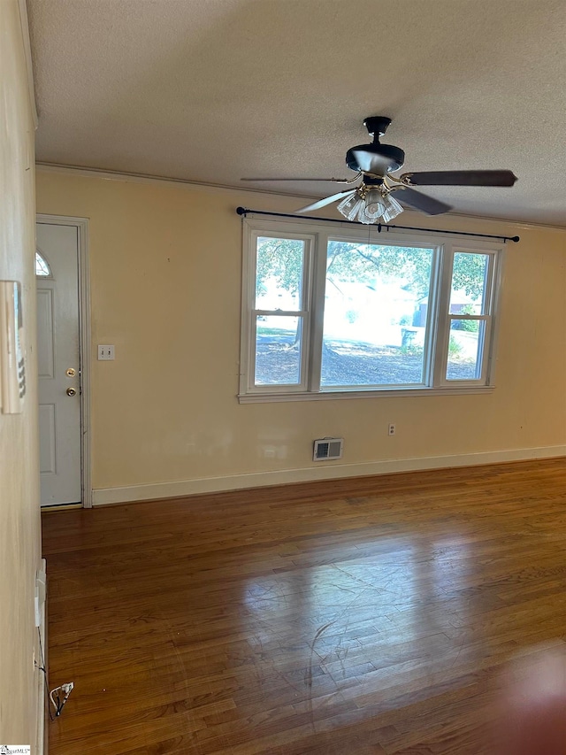 spare room with dark wood-type flooring, a healthy amount of sunlight, and a textured ceiling