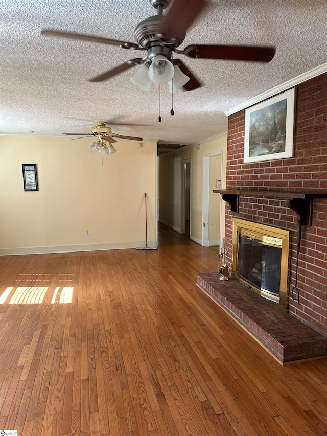 unfurnished living room with a brick fireplace, wood-type flooring, a textured ceiling, and ceiling fan