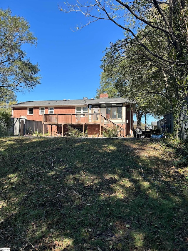 rear view of property featuring a lawn, a wooden deck, and a storage shed