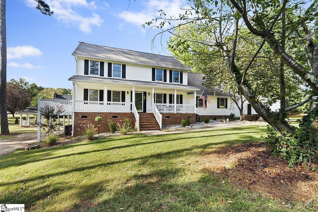 colonial inspired home with a porch, a front yard, and crawl space