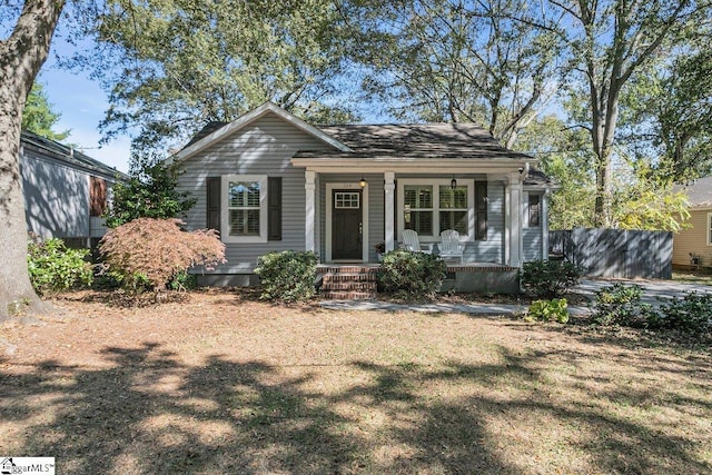 bungalow-style home featuring covered porch and a front lawn