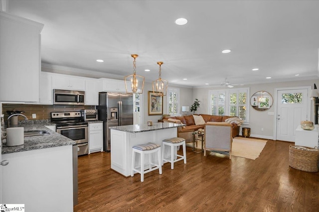 kitchen with dark hardwood / wood-style floors, stainless steel appliances, sink, a center island, and white cabinets