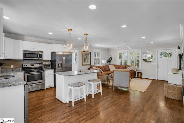 kitchen featuring a kitchen island, hanging light fixtures, stainless steel appliances, white cabinets, and dark hardwood / wood-style floors