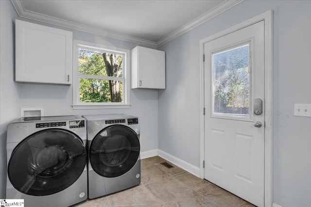 laundry area with crown molding, washing machine and dryer, and cabinets