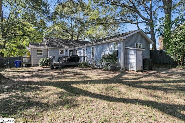 back of house with a yard, a deck, and an outdoor structure