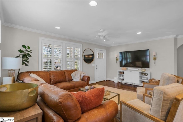 living room with ornamental molding, wood-type flooring, and ceiling fan