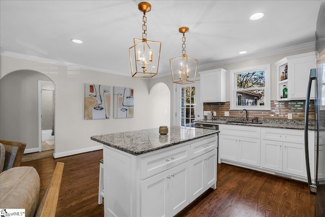 kitchen with a center island, sink, light stone counters, and white cabinets