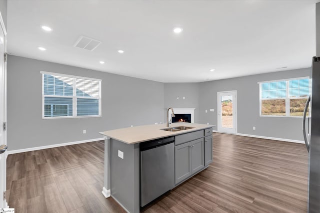 kitchen featuring dark wood-type flooring, a center island with sink, sink, gray cabinets, and appliances with stainless steel finishes