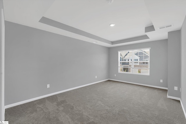 carpeted empty room featuring a tray ceiling