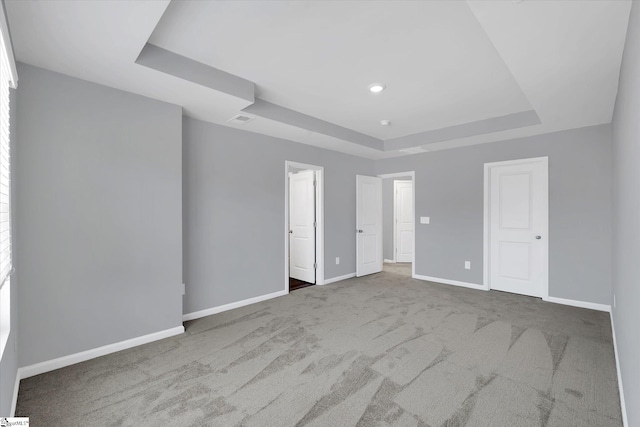 unfurnished bedroom featuring carpet flooring and a raised ceiling