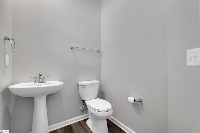 bathroom with toilet, hardwood / wood-style floors, and sink