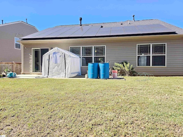 back of property featuring a patio area, a lawn, and solar panels