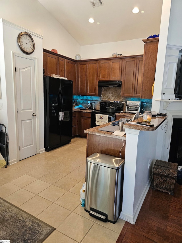 kitchen featuring tasteful backsplash, black appliances, kitchen peninsula, vaulted ceiling, and light tile patterned floors