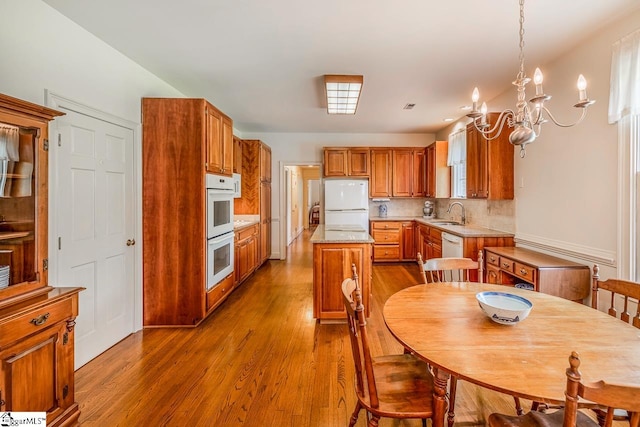 kitchen with decorative backsplash, wood-type flooring, decorative light fixtures, a center island, and white appliances