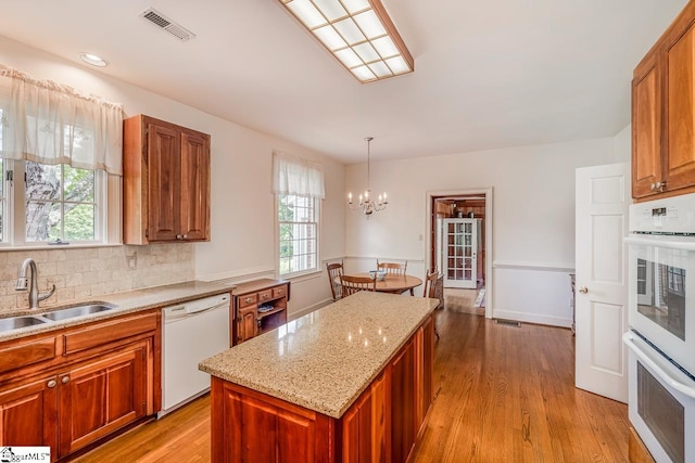 kitchen with decorative light fixtures, sink, light wood-type flooring, and white appliances