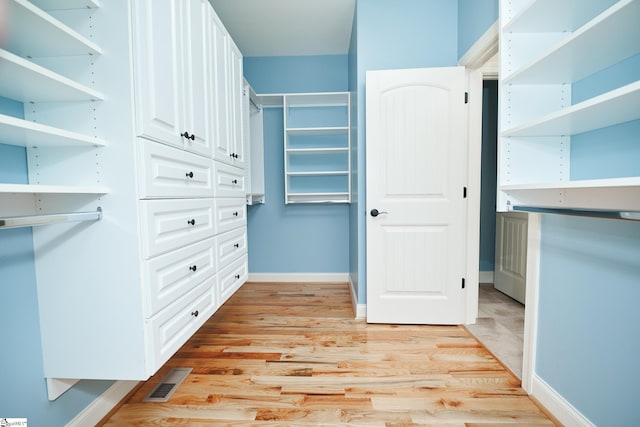 walk in closet with light hardwood / wood-style floors