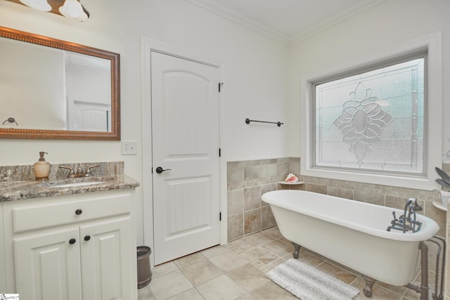 bathroom with tile patterned flooring, vanity, ornamental molding, a bathing tub, and tile walls