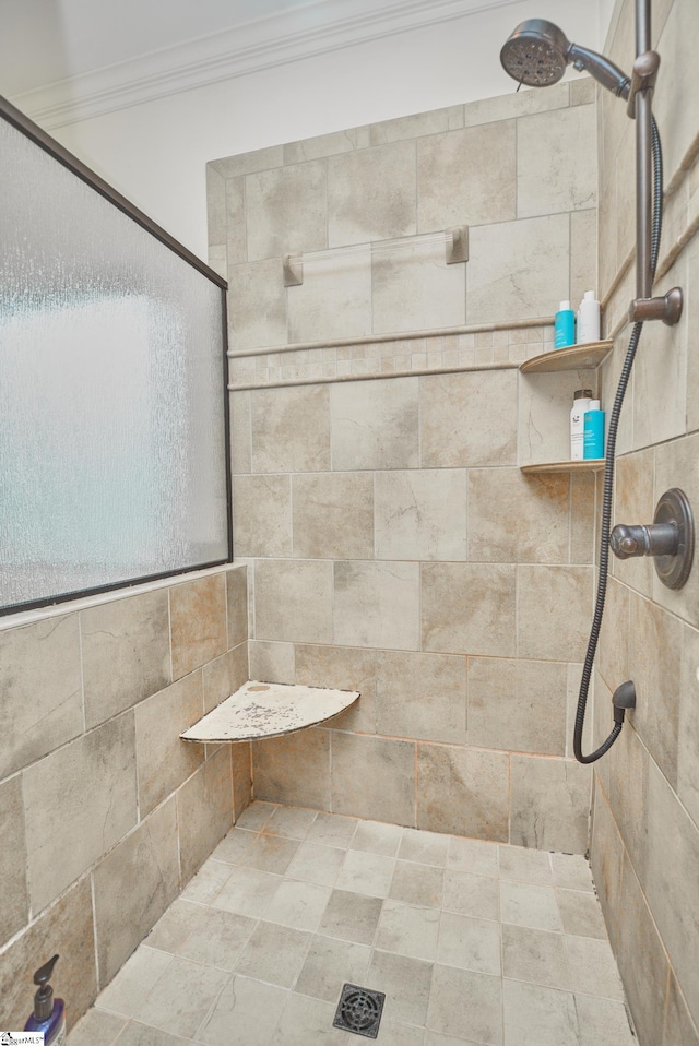 bathroom with tiled shower and crown molding