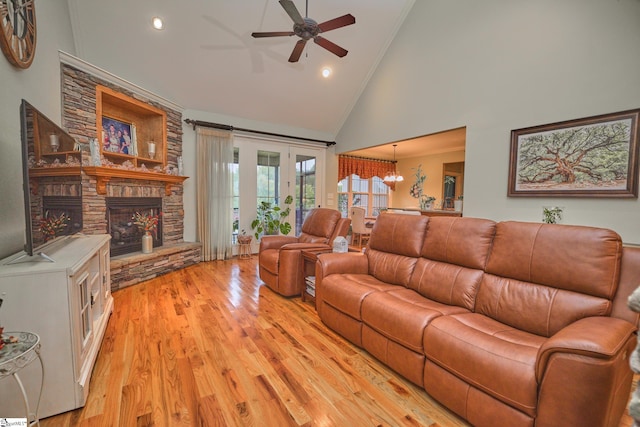 living room featuring ceiling fan with notable chandelier, a stone fireplace, light hardwood / wood-style floors, crown molding, and high vaulted ceiling