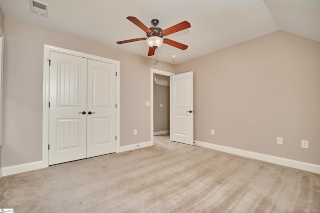 unfurnished bedroom featuring vaulted ceiling, light colored carpet, a closet, and ceiling fan