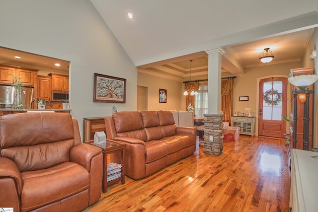 living room featuring decorative columns, light hardwood / wood-style flooring, a chandelier, and crown molding