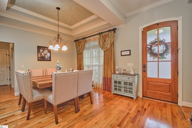 dining area featuring light hardwood / wood-style flooring, ornamental molding, and a tray ceiling