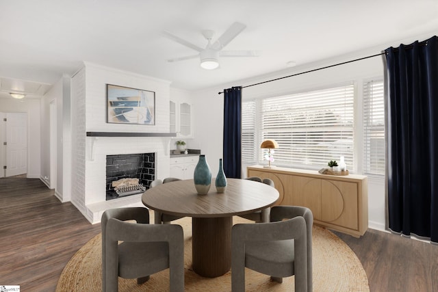 dining room with dark hardwood / wood-style floors, ceiling fan, and a brick fireplace