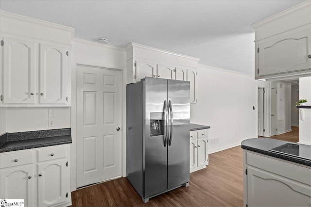 kitchen with ornamental molding, white cabinetry, stainless steel refrigerator with ice dispenser, and hardwood / wood-style flooring