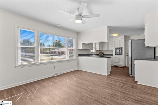 kitchen featuring oven, kitchen peninsula, ceiling fan, white cabinets, and dark hardwood / wood-style flooring